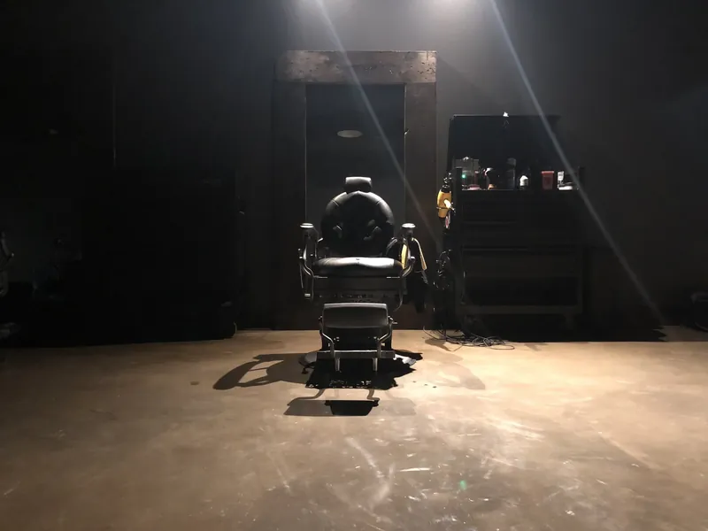 An empty vintage barber chair under a spotlight