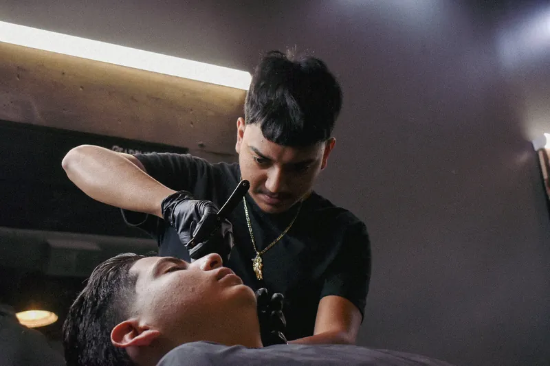 Barber holding a straight razor close to a reclined client’s face